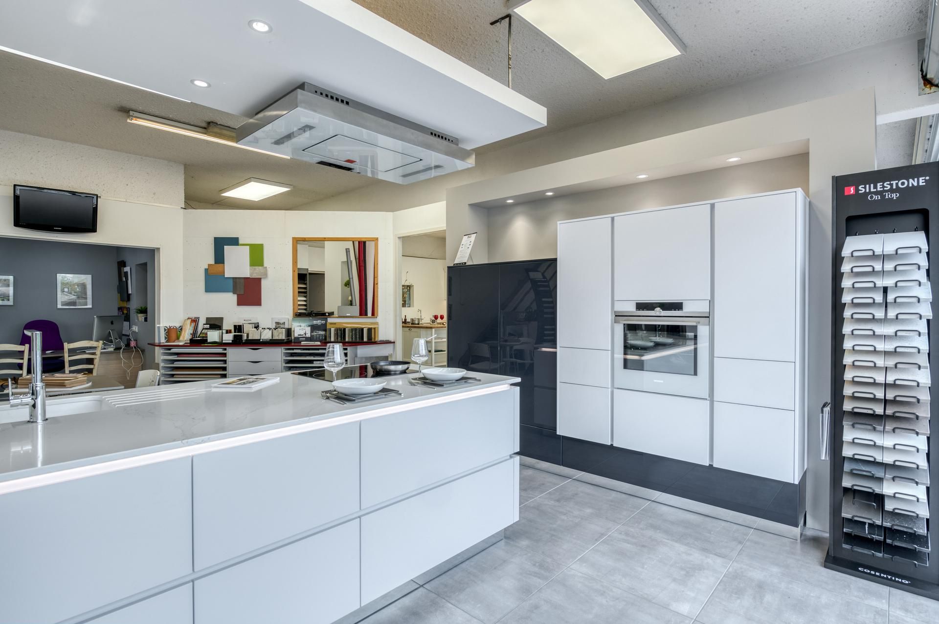 Salle d'exposition avec des cuisines blanches modernes avec îlot central