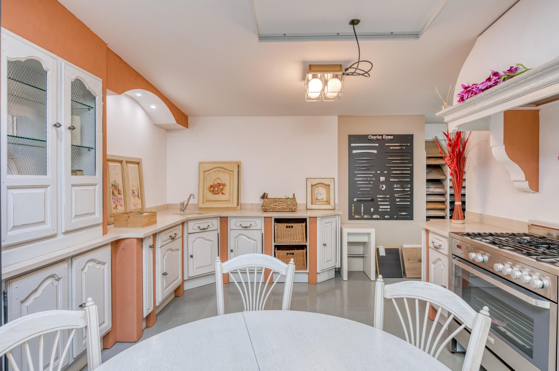Cuisine blanche lumineuse avec placards, cuisinière, table à manger et touches florales