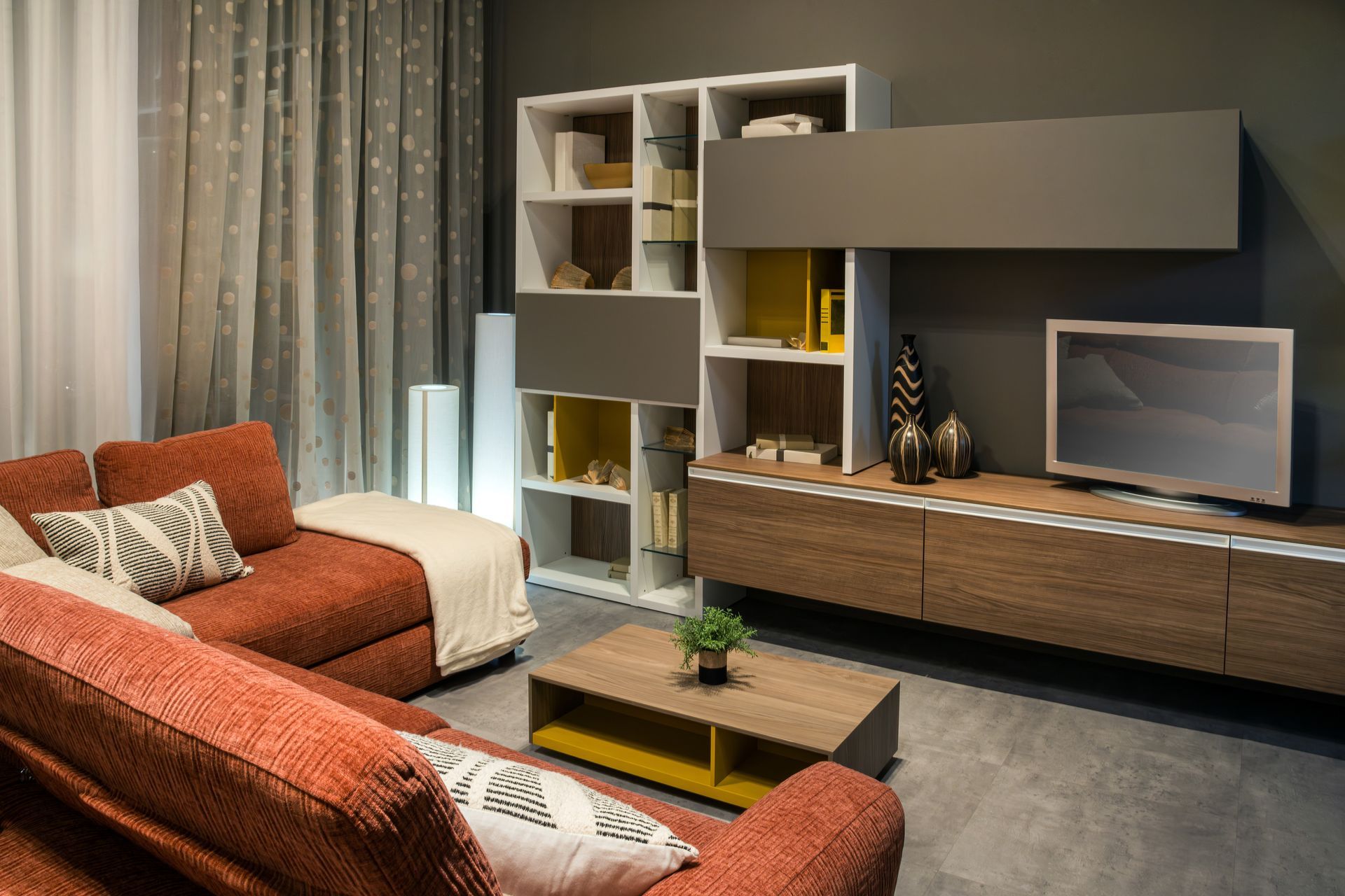 Salon moderne avec canapé orange, étagères blanches et meuble TV mural