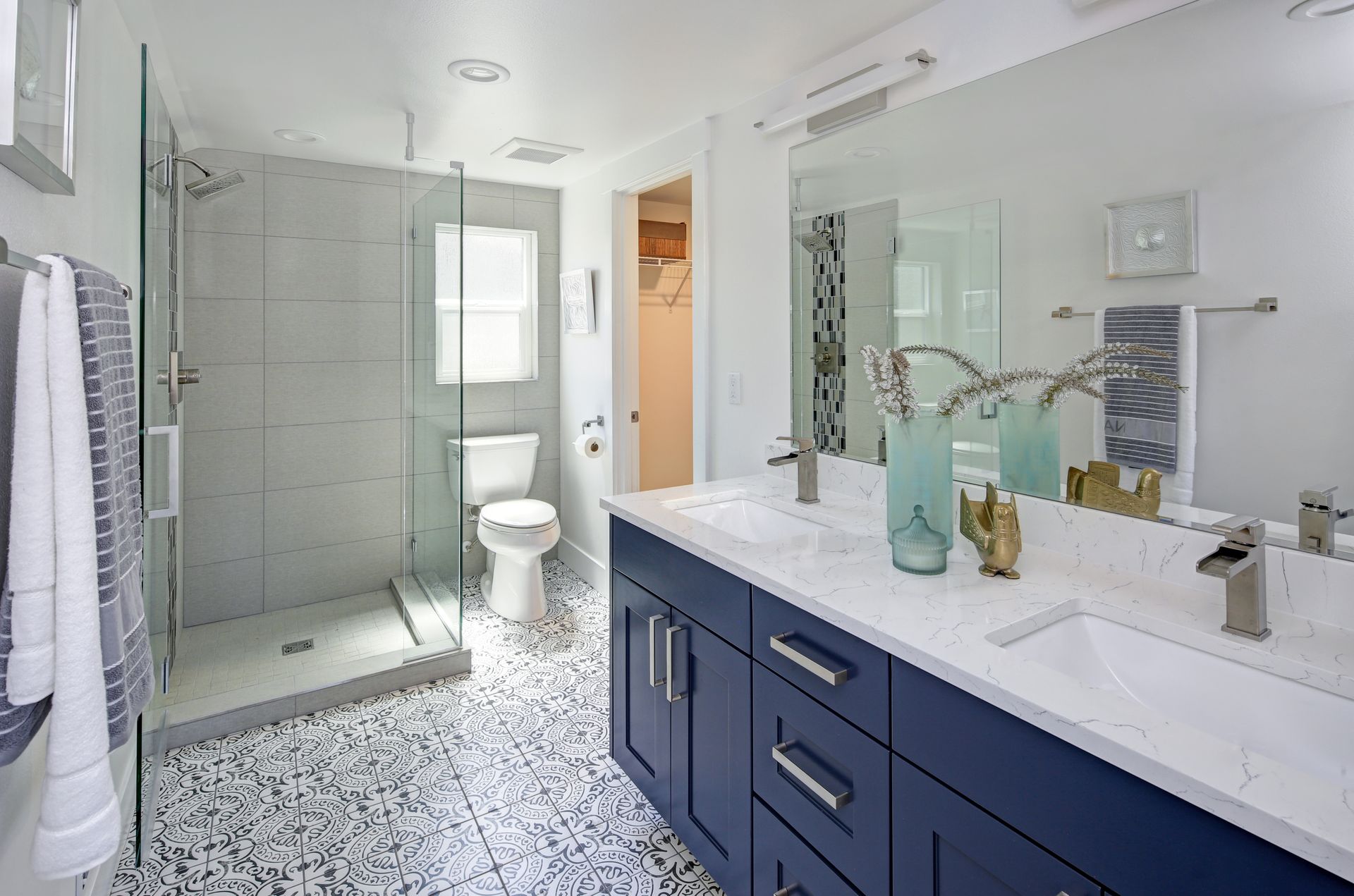 Salle de bains moderne et lumineuse avec douche en verre, toilettes et meuble lavabo bleu avec comptoir blanc