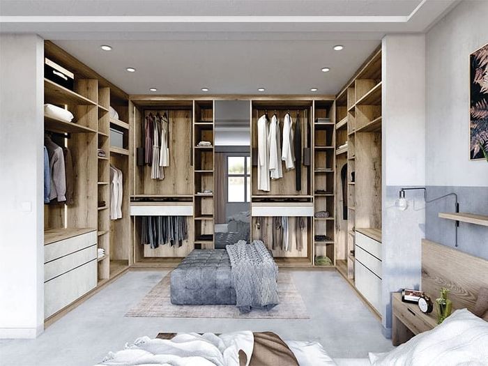 Dressing moderne avec étagères ouvertes, penderie, tiroirs et pouf central sous un éclairage encastré