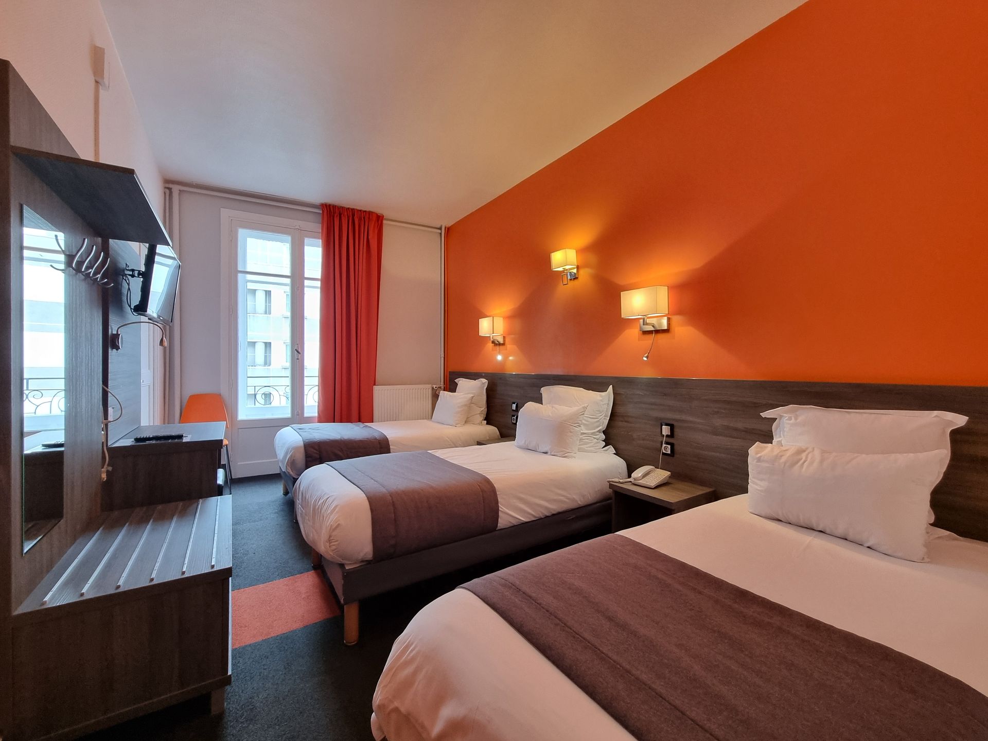 Chambre avec 3 lits simples de couleur orange