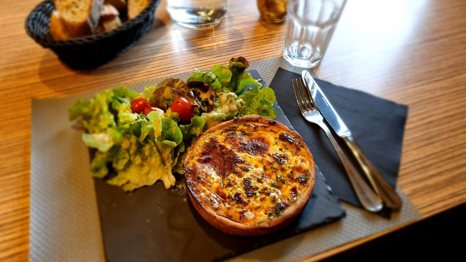 Quiche dans une assiette en ardoise avec de la salade et des tomates cerises