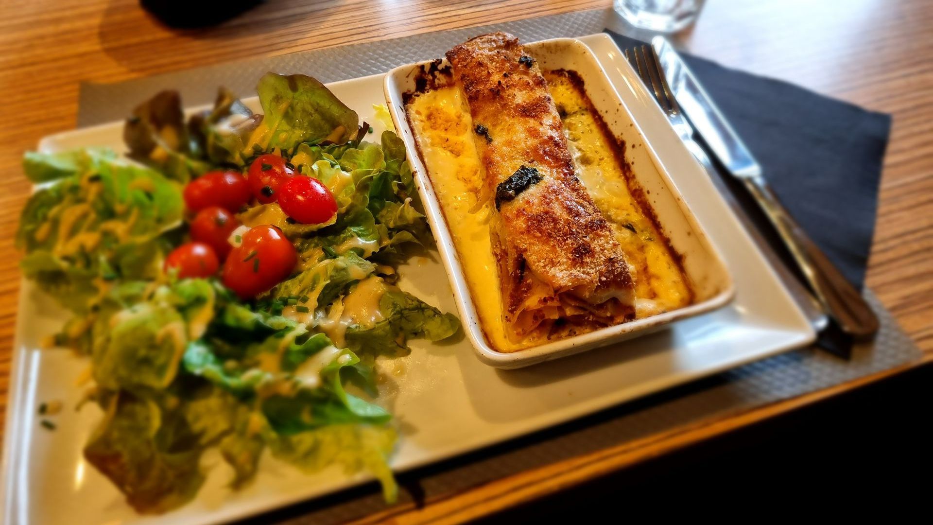 Plat gratiné à côté d'une salade avec des tomates