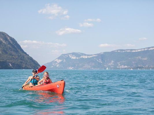 Deux enfants dans un kayak sur un lac avec des montagnes autour