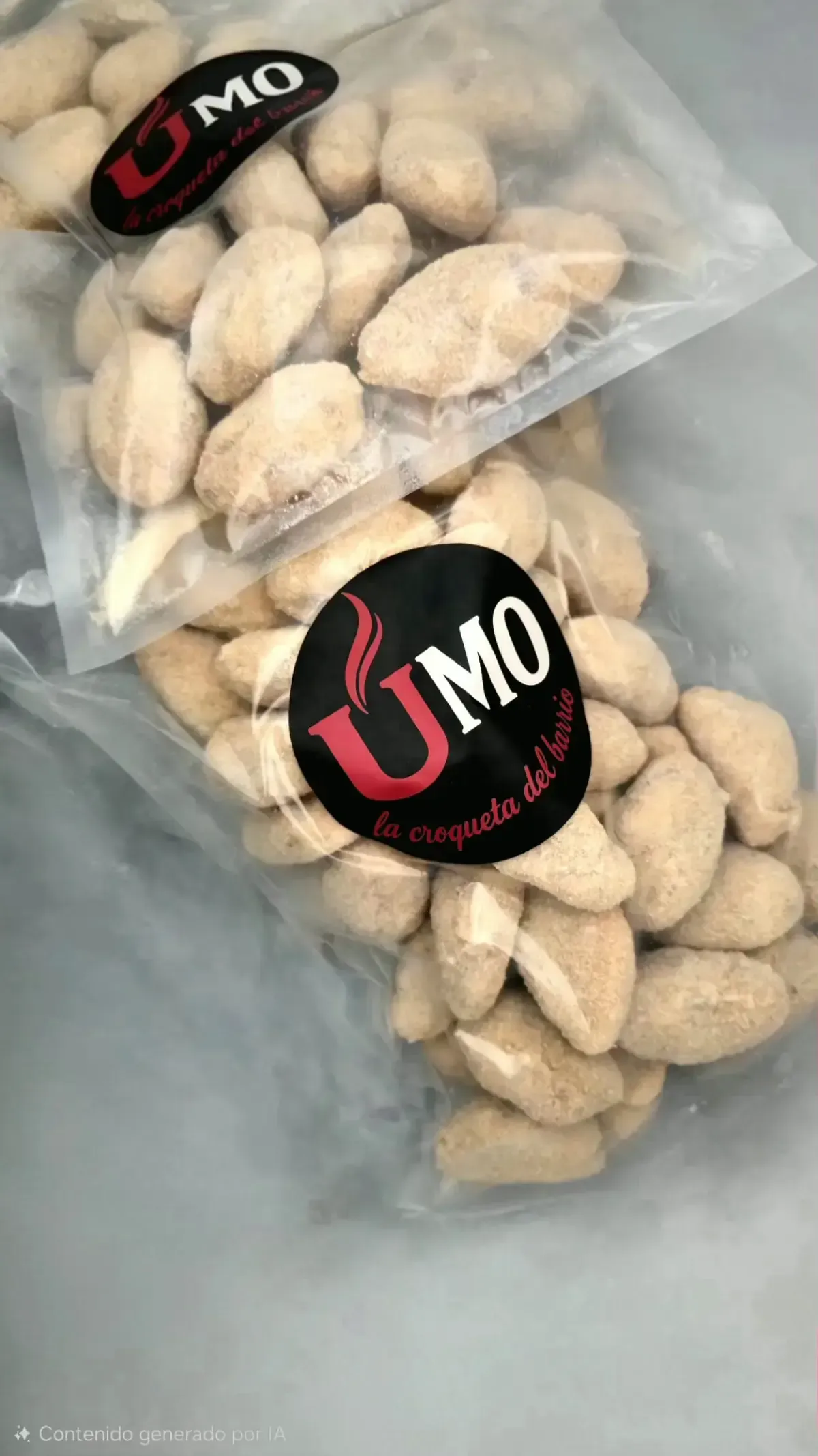 Una bandeja metálica llena de croquetas recién fritas y doradas reposa sobre una encimera de cocina de acero inoxidable.