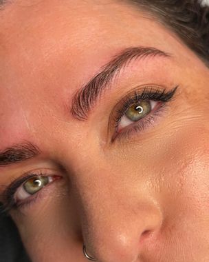 Un primer plano del rostro de una mujer con ojos verdes y un anillo en la nariz.