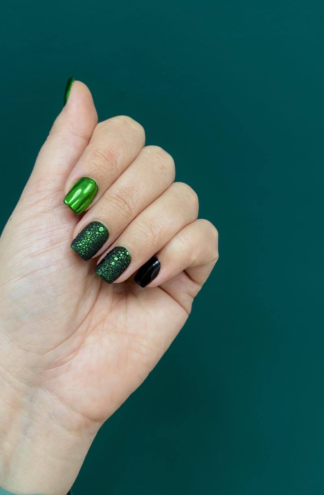 Un primer plano de la mano de una mujer con uñas de color púrpura y amarillo.