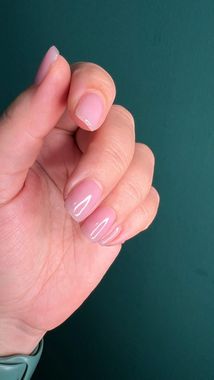 Un primer plano de la mano de una persona con uñas rosadas.