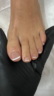Un primer plano del pie de una mujer con manicura francesa.