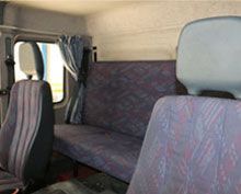 El interior de un autobús con asientos morados y una ventana.