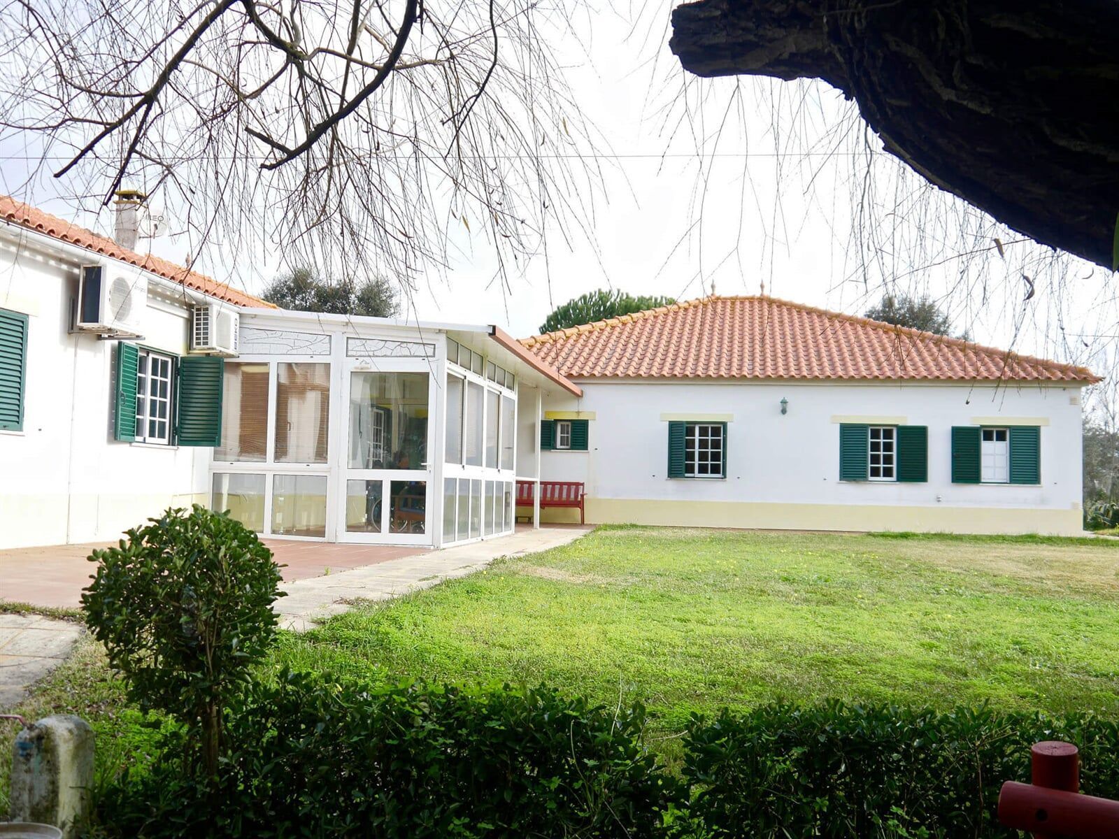 Uma casa branca com persianas verdes e um telhado de telha vermelha