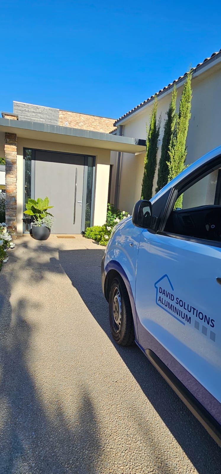 Une camionnette blanche garée sur une allée de gravier devant une maison.