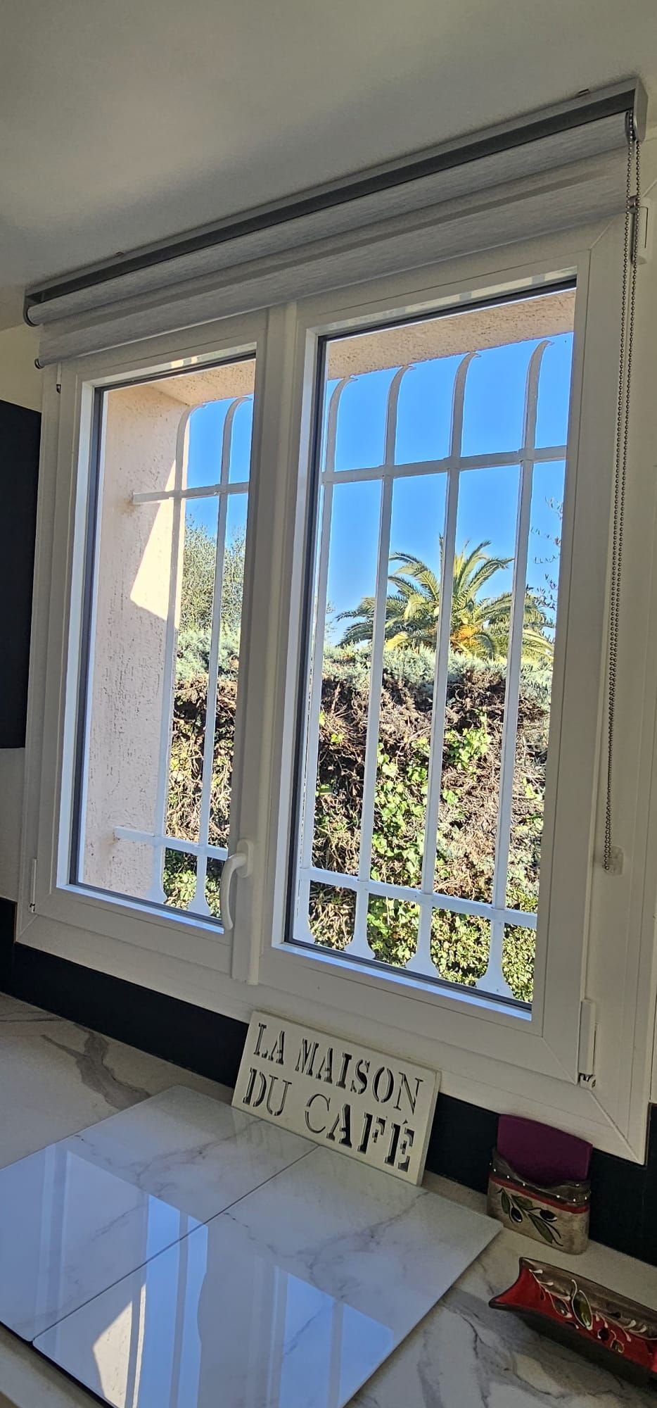 Fenêtre à barres blanches et store enrouleur à l'intérieur du bâtiment.