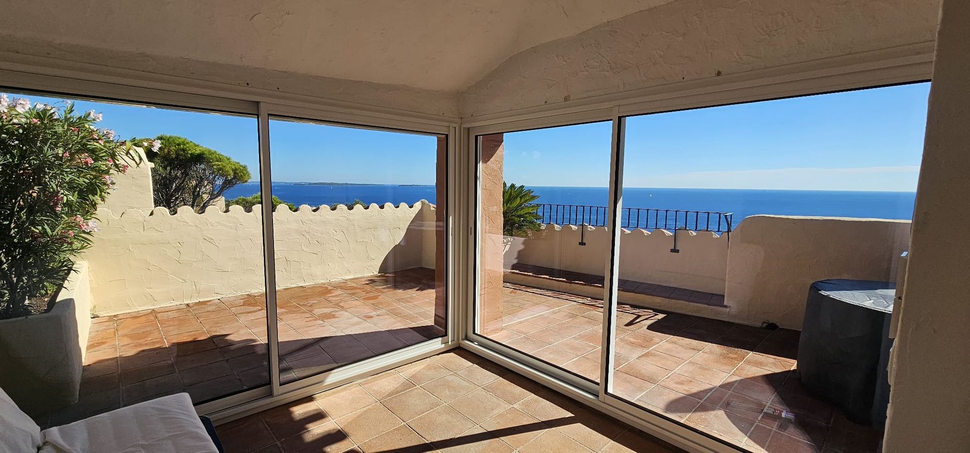 Une chambre avec de grandes fenêtres donnant sur une mer et un ciel bleus.