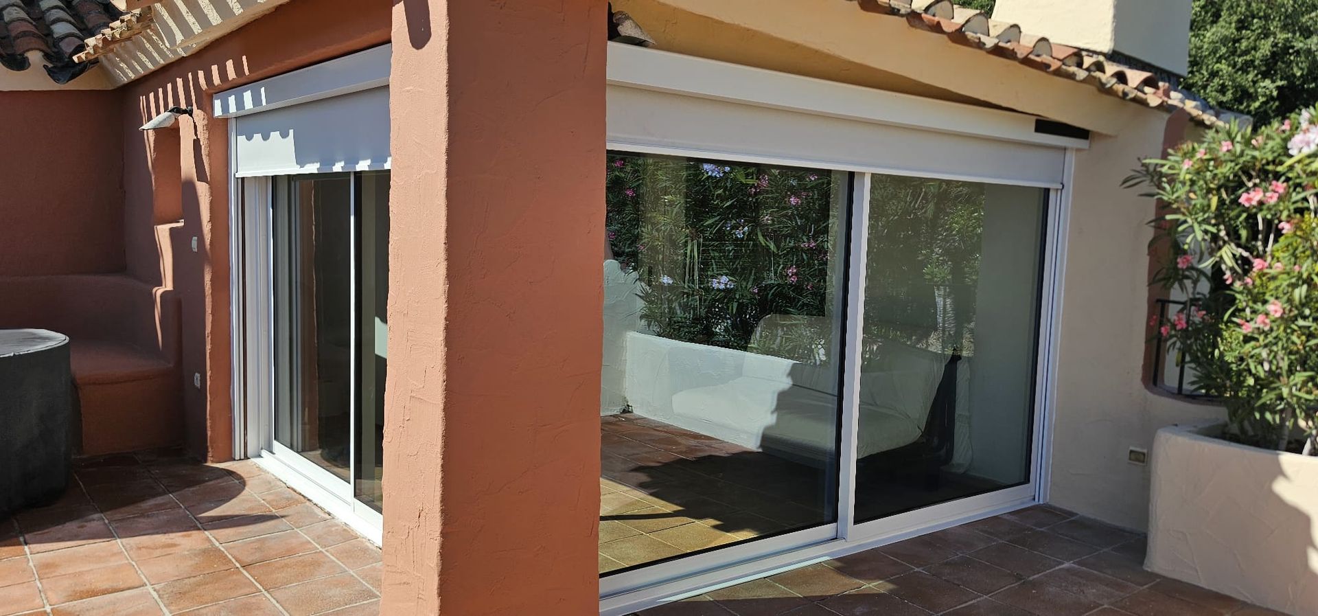 Véranda avec piliers bruns et stores partiellement baissés.