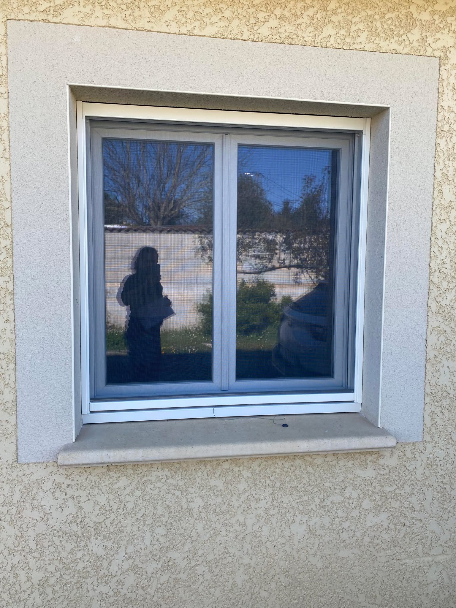 Extérieur d'un bâtiment avec une grande fenêtre où l'on peut voir le mot « Quori ». Façade en pierre couleur crème.
