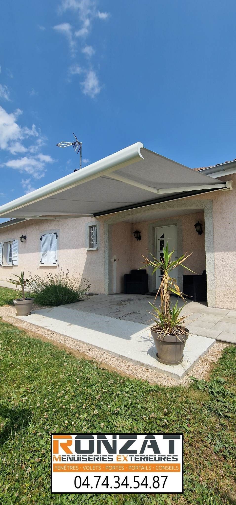 Maison avec auvent et ciel avec avion. Pelouse et panneau avec numéro de téléphone.
