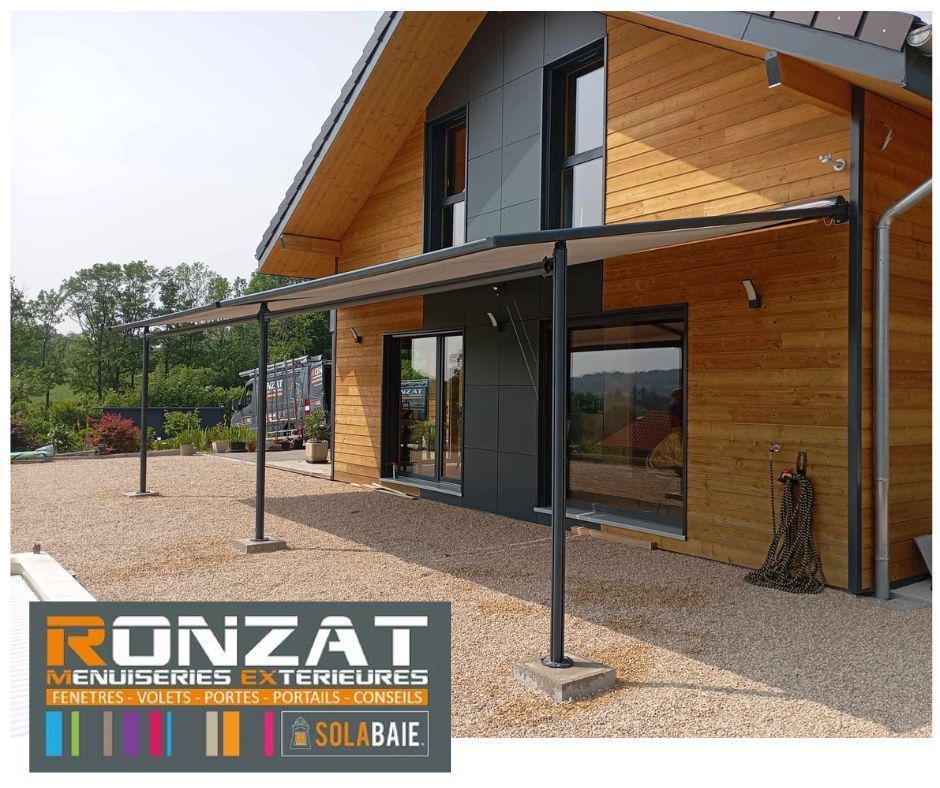 Maison moderne avec bardage en bois et gris, terrasse en gravier et porche couvert.