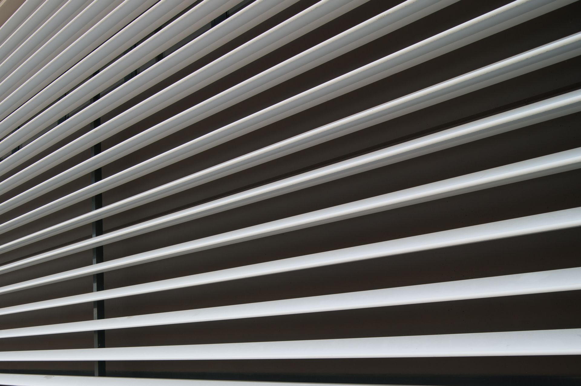Stores horizontaux blancs inclinés sur une surface brun foncé.