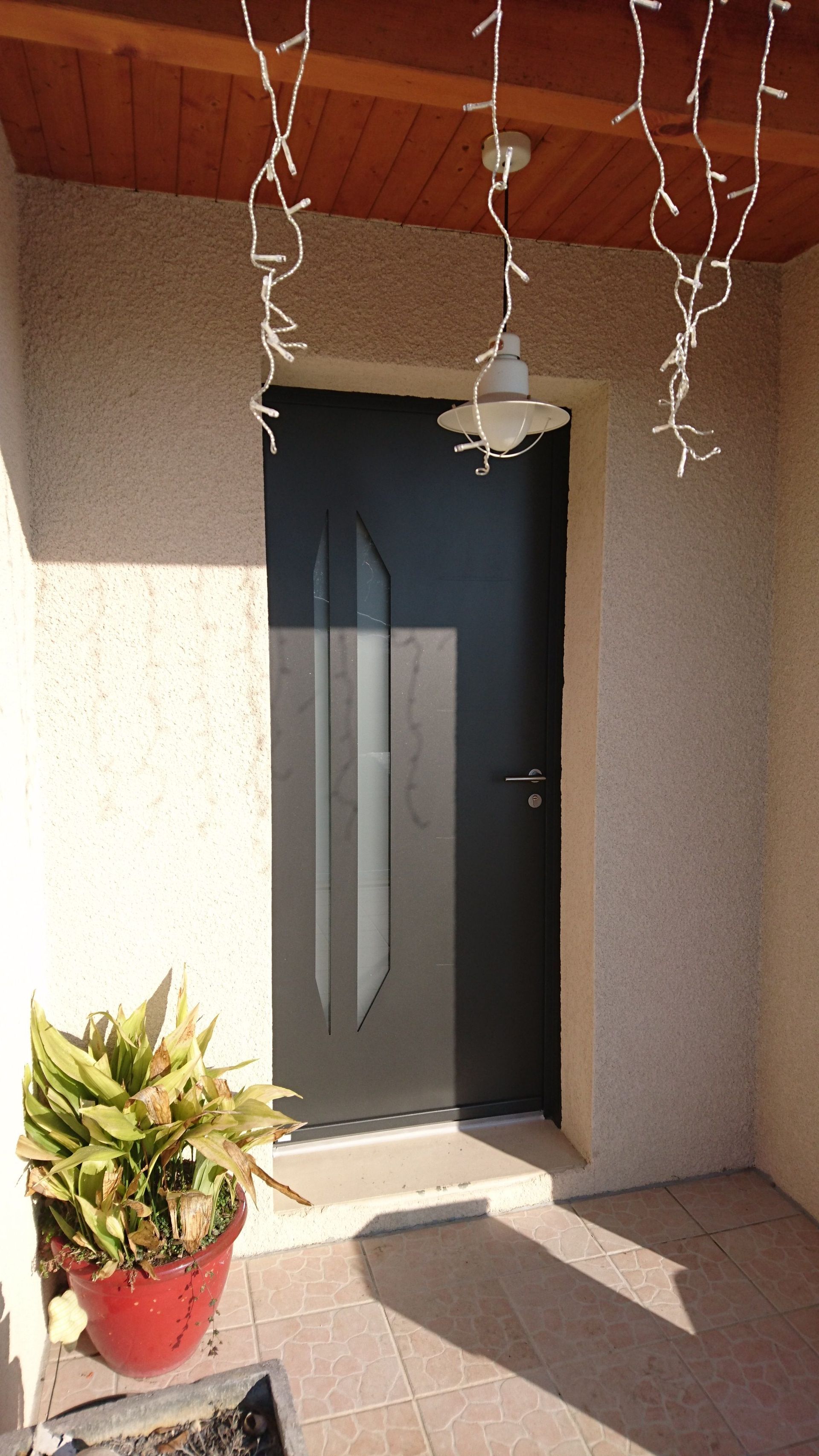 Porte d'entrée blanche avec fenêtre ovale, parquet clair et rangements bleus.