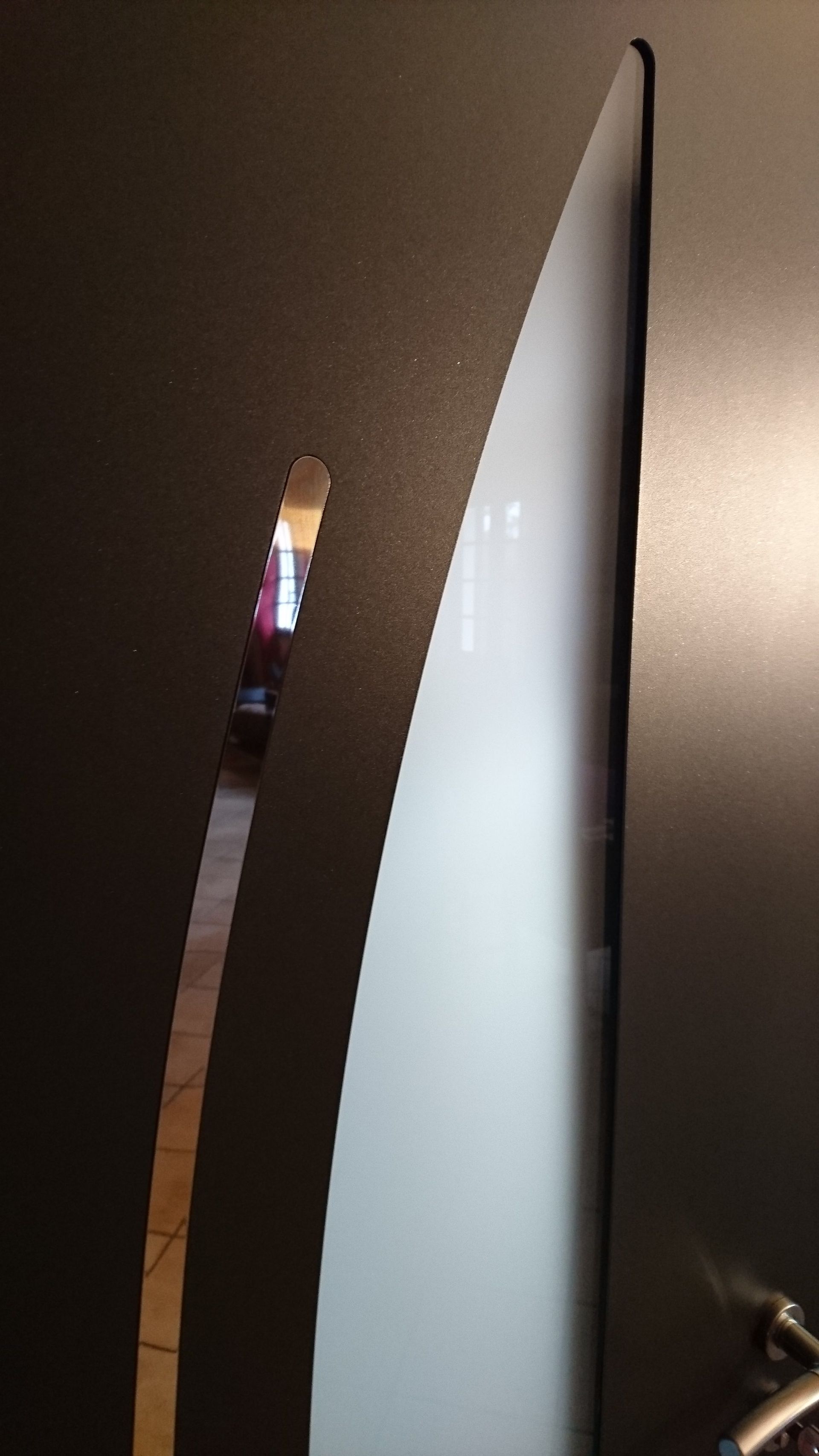 Écran d'ordinateur incurvé placé à côté d'une surface sombre ; la vue de côté montre l'affichage blanc de l'écran.