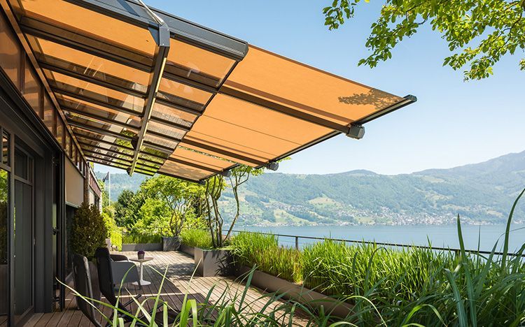 Terrasse avec store rétractable donnant sur le lac et les montagnes.