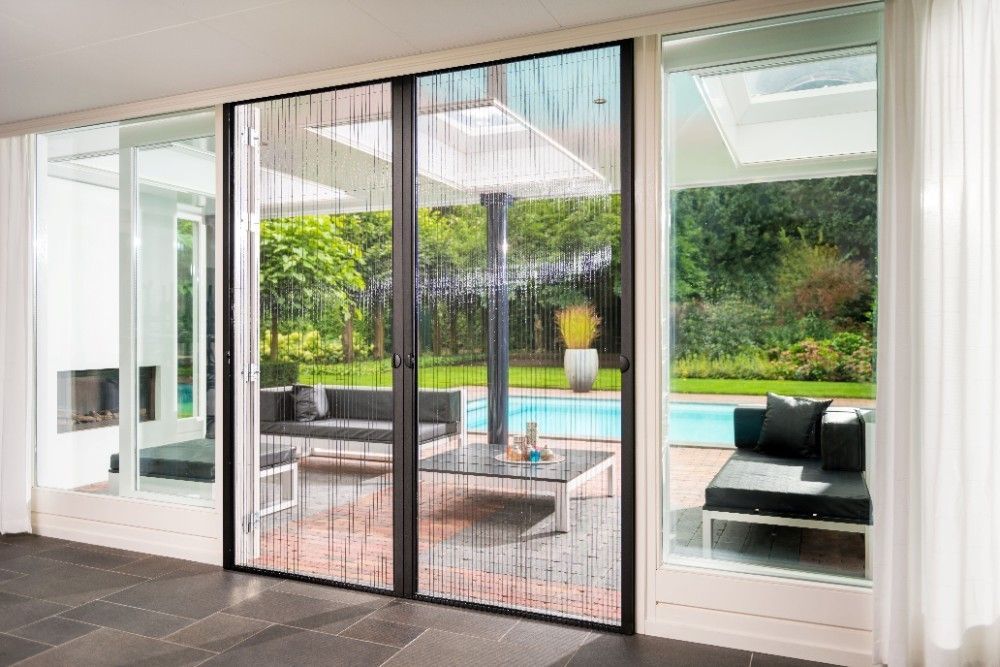 Porte-fenêtre coulissante donnant sur une terrasse meublée avec piscine.