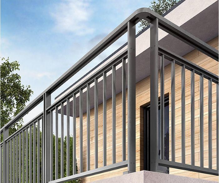 Rambarde de balcon en métal gris sur la façade d'un bâtiment, avec barres verticales et angles arrondis.