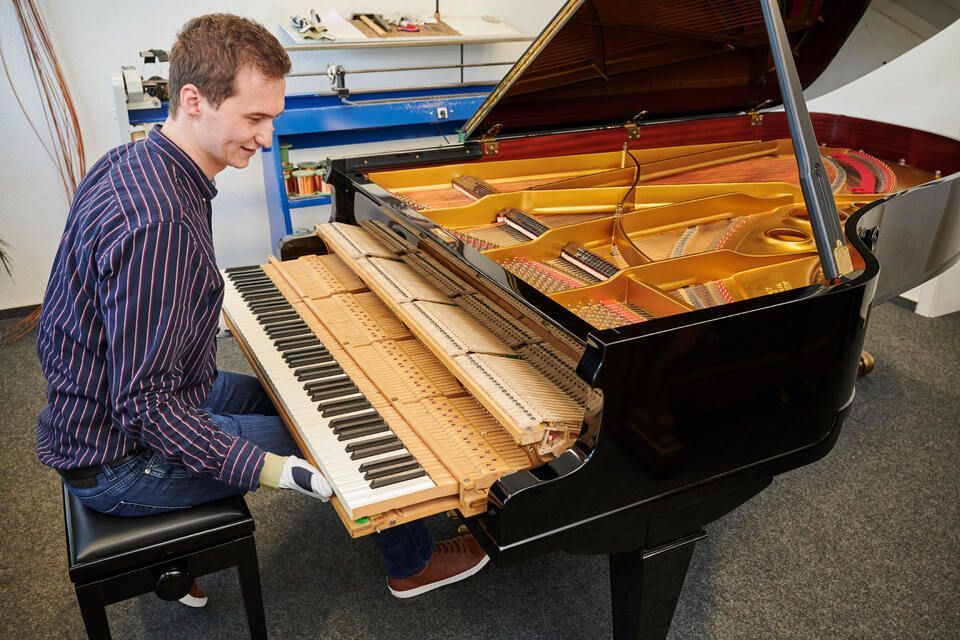Adrian Heß arbeitet an einem Klavier, Foto von Harald Schlecker