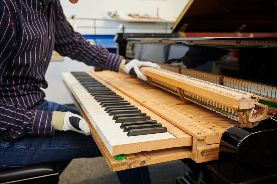 Adrian Heß arbeitet an einem Klavier, Foto von Harald Schlecker