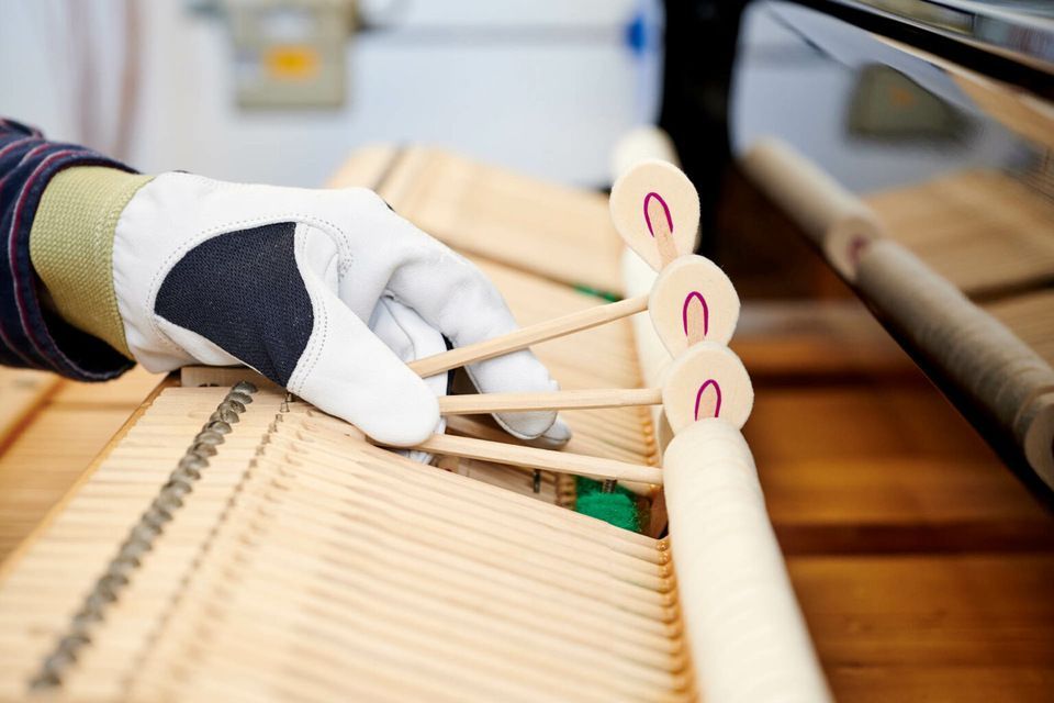 Adrian Heß arbeitet an einem Klavier, Foto von Harald Schlecker