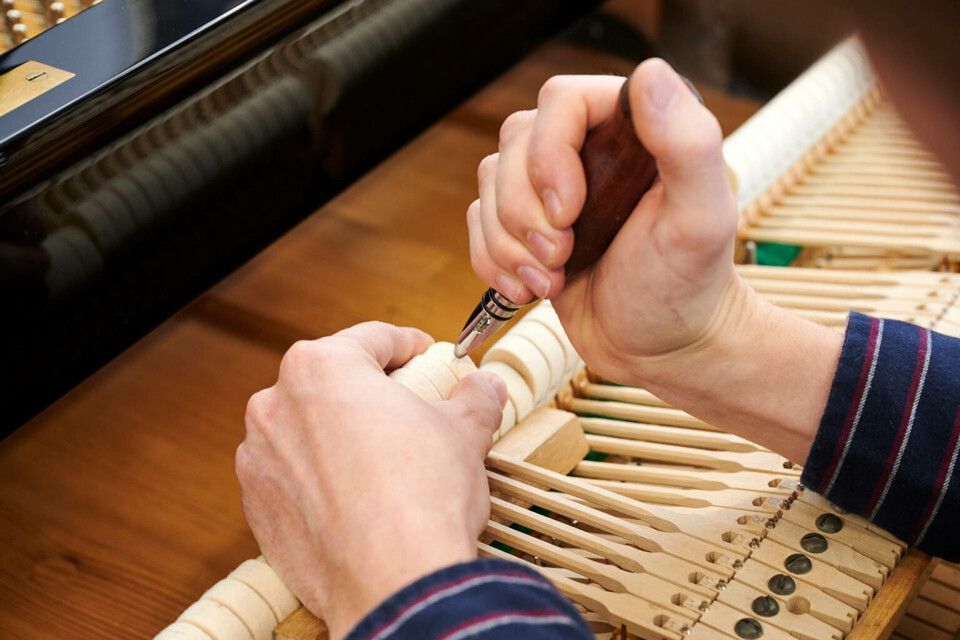 Adrian Heß arbeitet an einem Klavier, Foto von Harald Schlecker