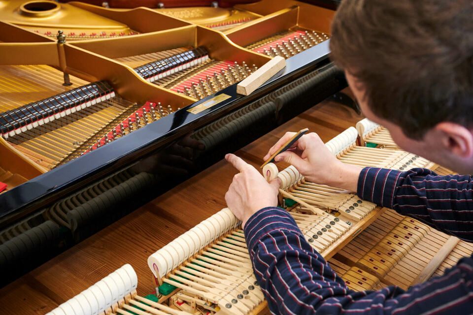 Adrian Heß arbeitet an einem Klavier, Foto von Harald Schlecker