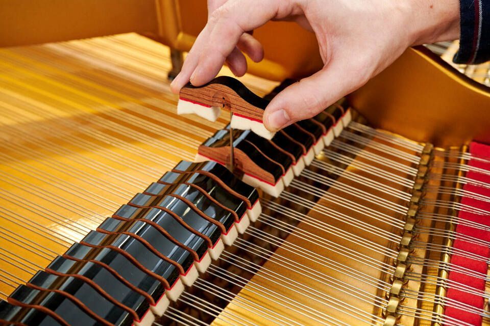 Adrian Heß arbeitet an einem Klavier, Foto von Harald Schlecker