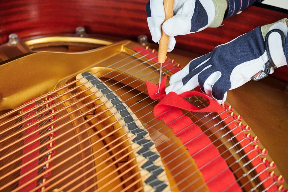 Adrian Heß arbeitet an einem Klavier, Foto von Harald Schlecker