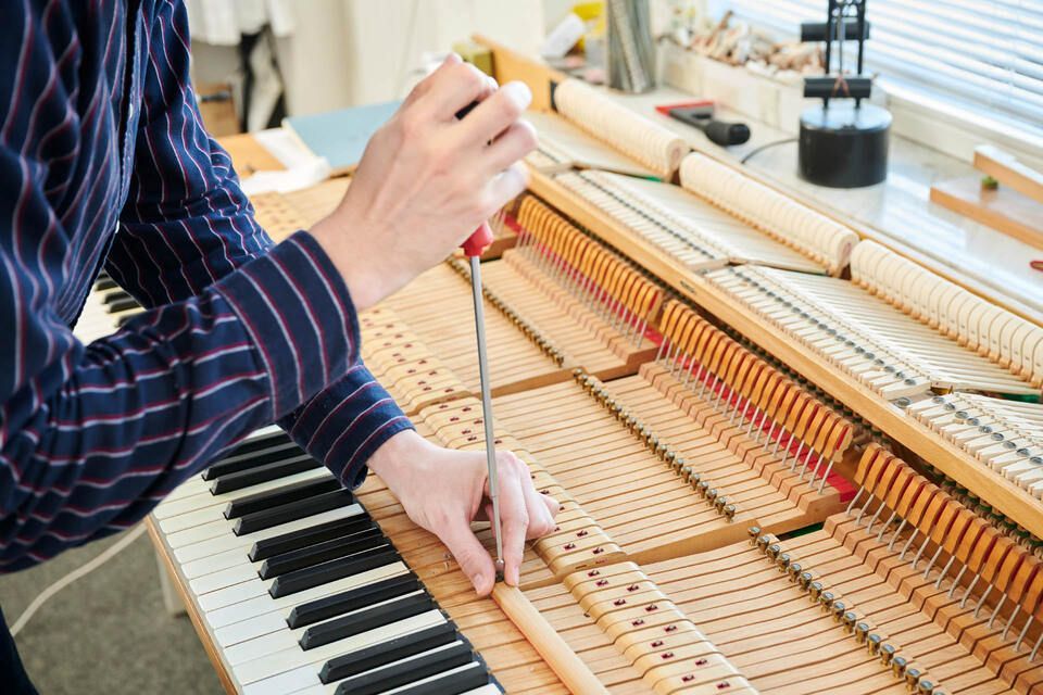 Adrian Heß arbeitet an einem Klavier, Foto von Harald Schlecker