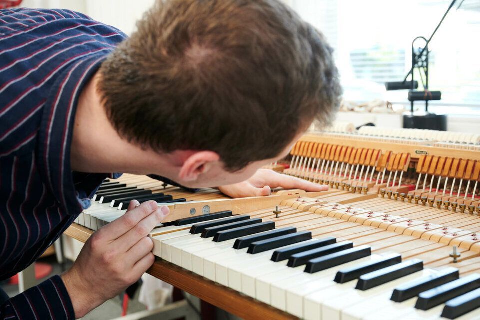 Adrian Heß arbeitet an einem Klavier, Foto von Harald Schlecker
