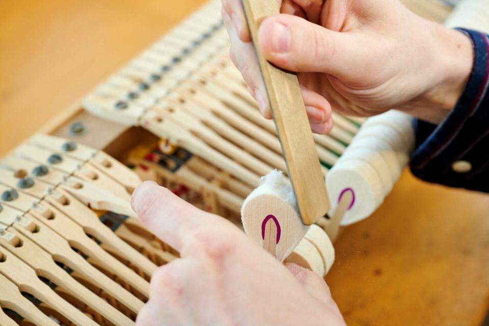 Adrian Heß arbeitet an einem Klavier, Foto von Harald Schlecker