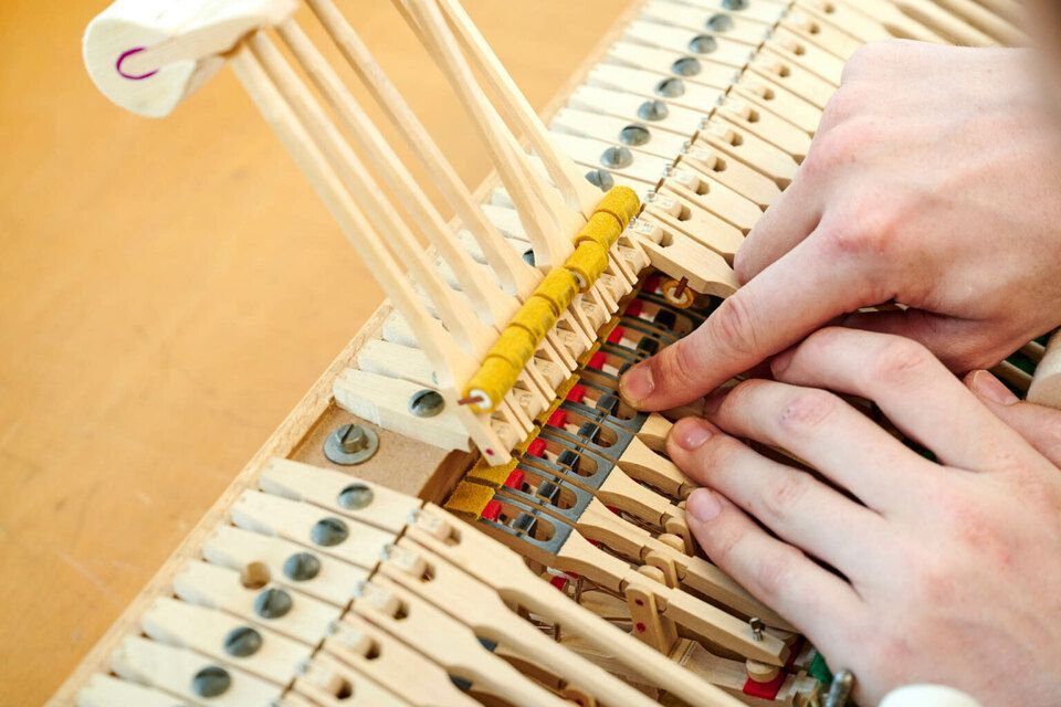 Adrian Heß arbeitet an einem Klavier, Foto von Harald Schlecker