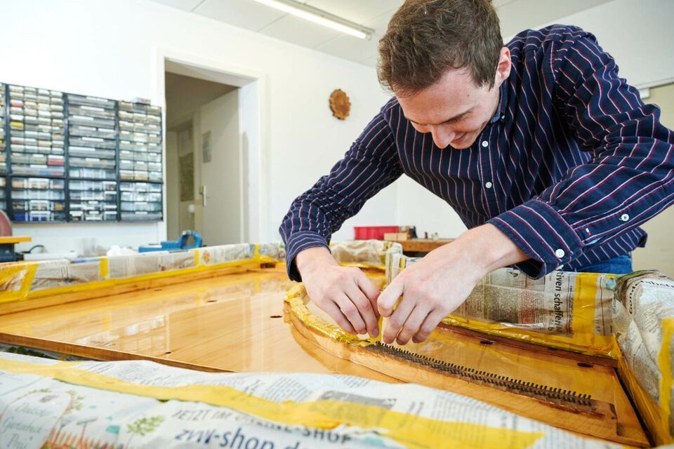 Adrian Heß arbeitet an einem Klavier, Foto von Harald Schlecker