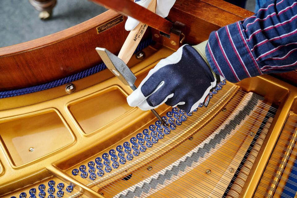 Adrian Heß arbeitet an einem Klavier, Foto von Harald Schlecker