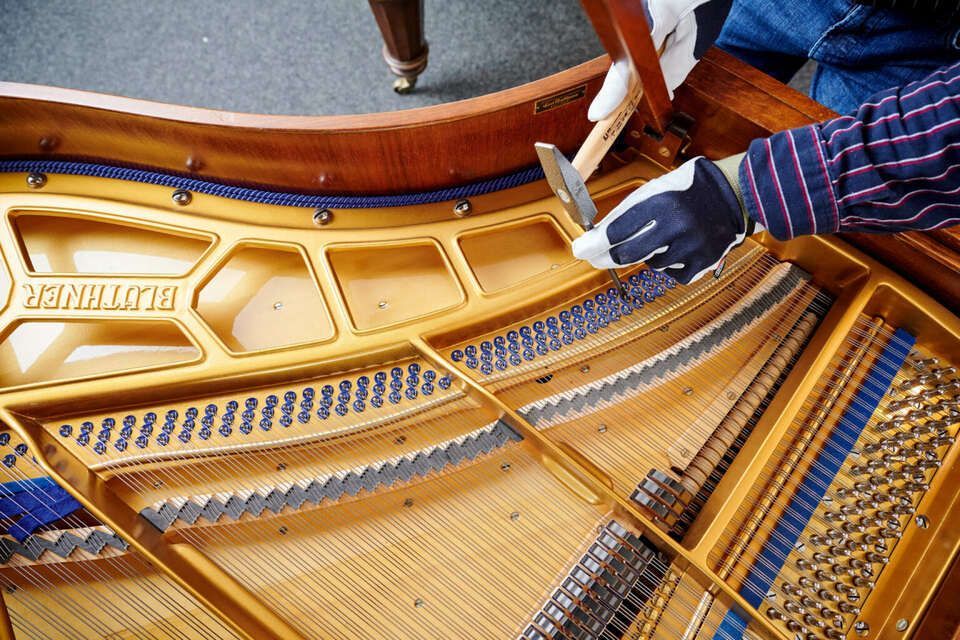 Adrian Heß arbeitet an einem Klavier, Foto von Harald Schlecker