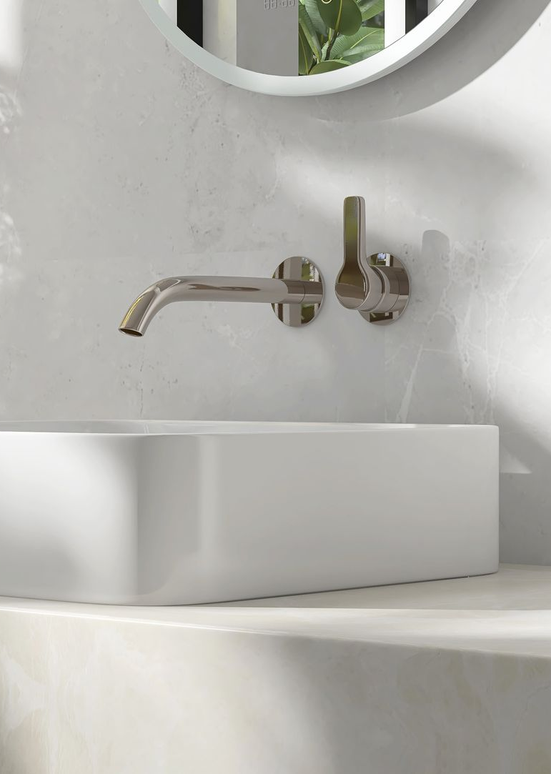 Un robinet mural moderne en nickel brossé au-dessus d'un lavabo rectangulaire blanc.