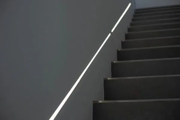 Treppe mit Licht, das eine diagonale Linie an der Wand beleuchtet und so einen Kontrast erzeugt.