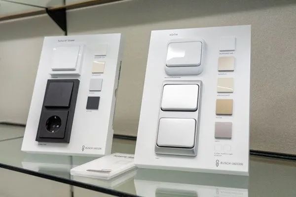 Zwei weiße Anzeigetafeln mit elektrischen Schaltern und Steckdosen in verschiedenen Farben auf einem Regal.