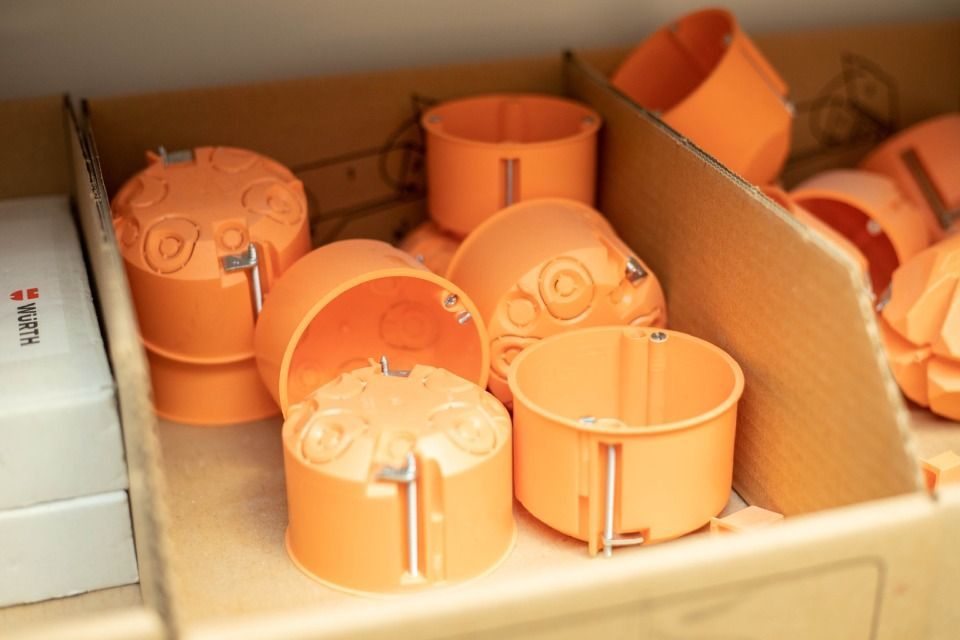 Orangefarbene elektrische Anschlusskästen in einem Kartonbehälter.