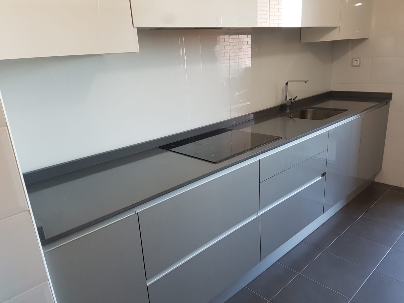 Una cocina con gabinetes grises y encimeras negras.