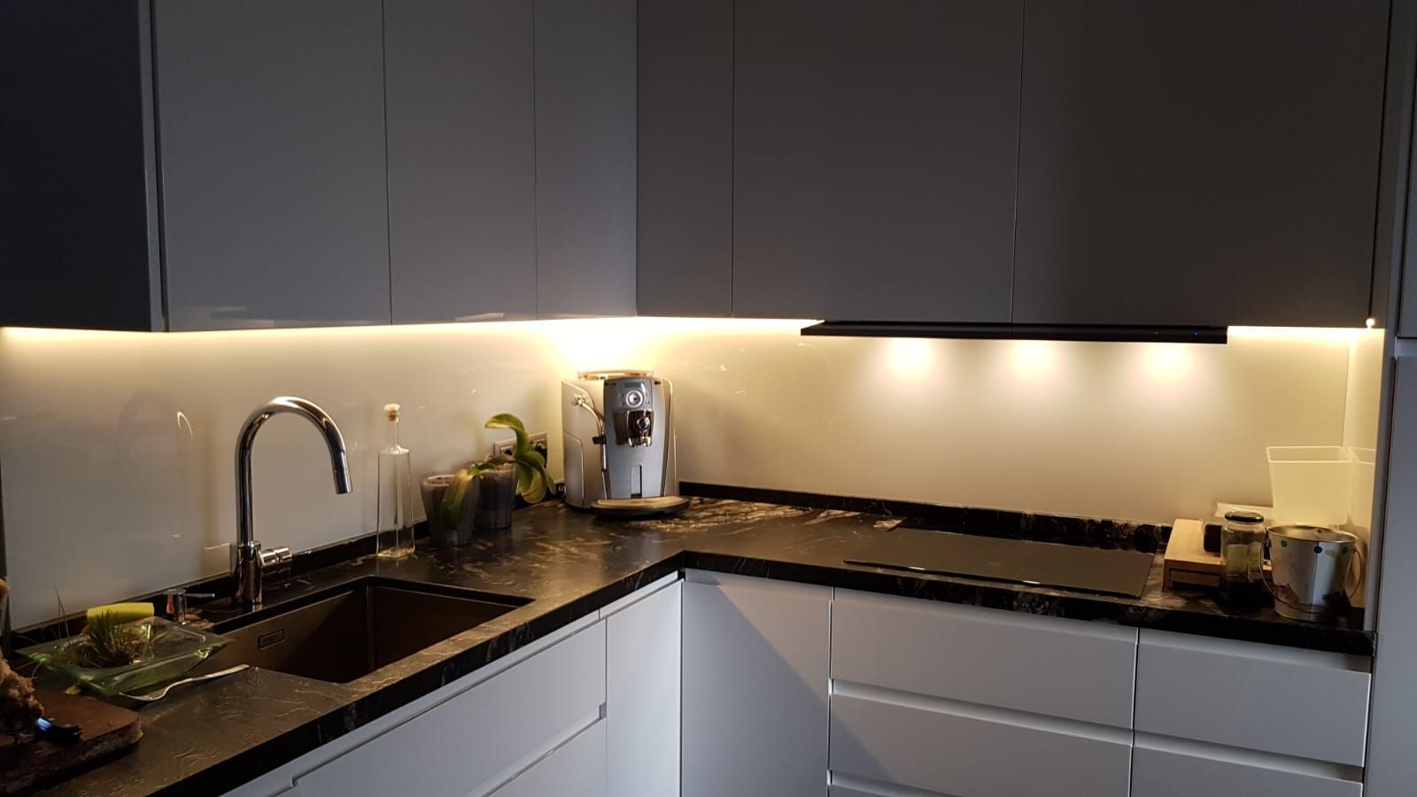 Una cocina con gabinetes blancos, encimeras negras, un fregadero y una estufa.