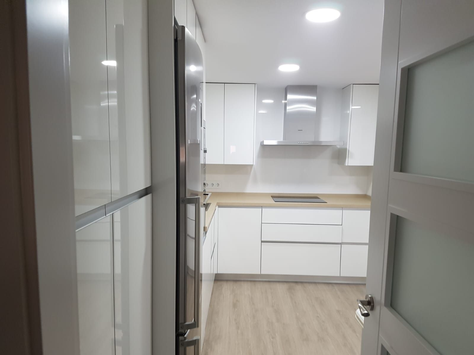 Una cocina con gabinetes blancos y electrodomésticos de acero inoxidable.